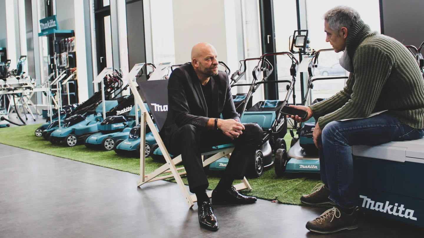 Christian Will, Head of Sales bei Makita, spricht mit Christian Clerici von vibe in einem Ausstellungsraum mit Makita-Geräten im Hintergrund.