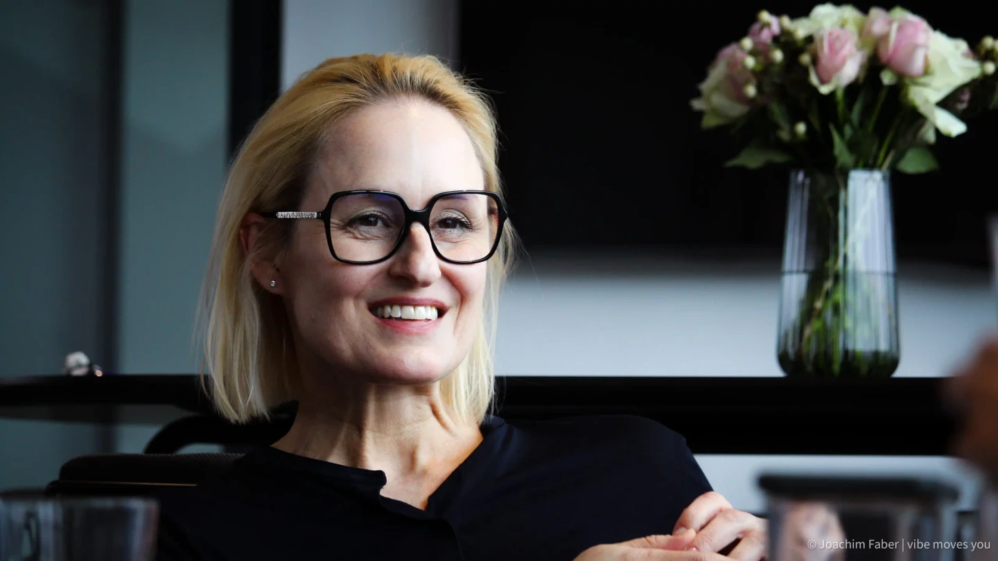 Ruth Moss, Head of Marketing & Communications bei CRIF, lächelt während eines Gesprächs in einem modernen Innenraum.